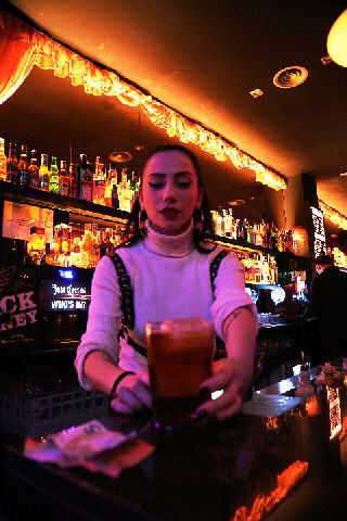 tired female bartender making drink for impatient customers