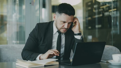 man at desk looking drained and on his phone