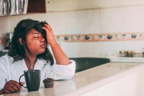 woman thinking about work deadline with coffee and hand on forehead