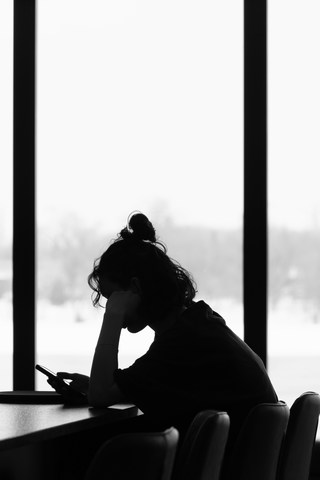 woman at work desk looking burned out in front of window