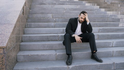 man stressed from work sitting outside on stairs
