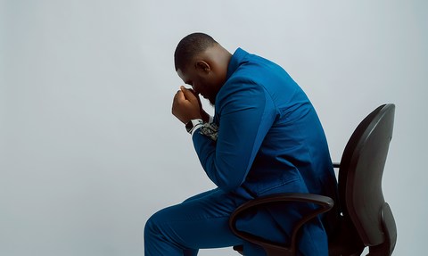tired and emotionally exhausted man leaned over in office chair